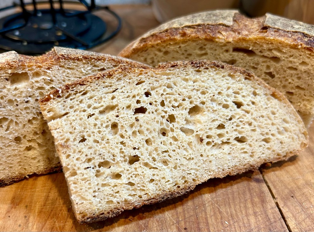 Three slices of freshly baked bread showcasing a crusty exterior and a soft, airy interior on a wooden surface.